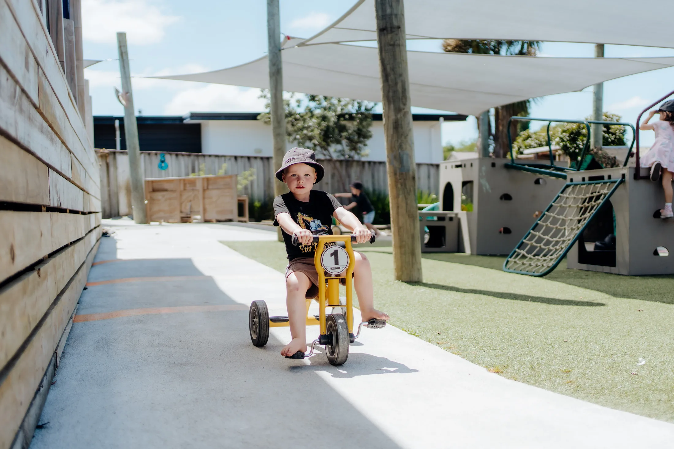 A child riding through the Tiny Legends outdoor play space