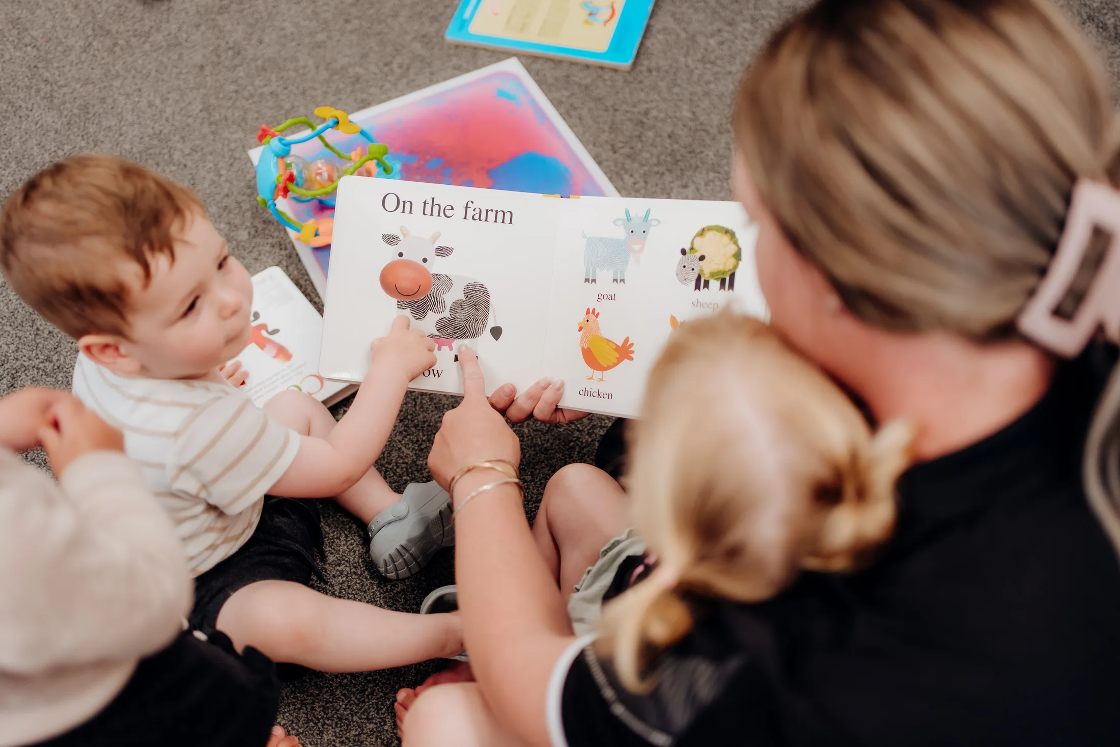 A Mini Legends kaiako reading with two young children
